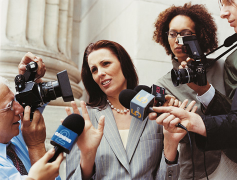 News Reporters Interviewing a Woman in a Suit Accompanied by Photographers